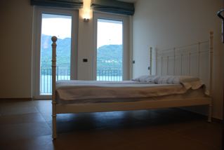 Master Bedroom of Villa Heureka with panoramic view of Lake Orta and the wooded hills on the other side of the lake.